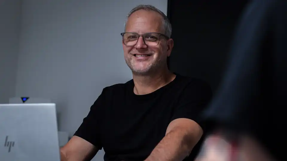 Eine Person sitzt vor einem Laptop und lächelt