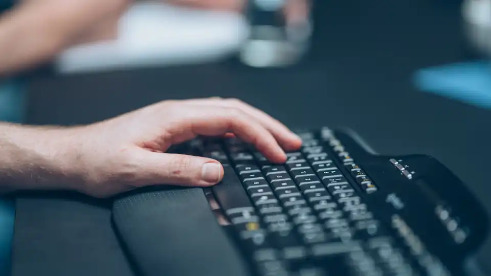 Eine Hand auf einer schwarzen Computertastatur