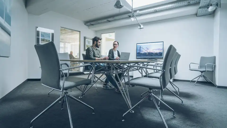 Zwei Personen sitzen an einem großen Besprechungstisch