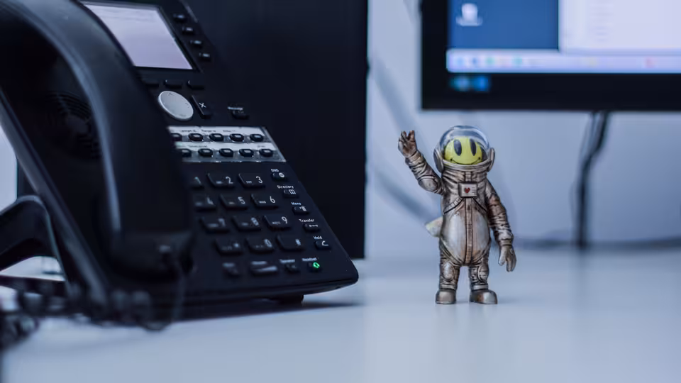 Ein Telefon, daneben eine lustige Figur im Raumanzug.