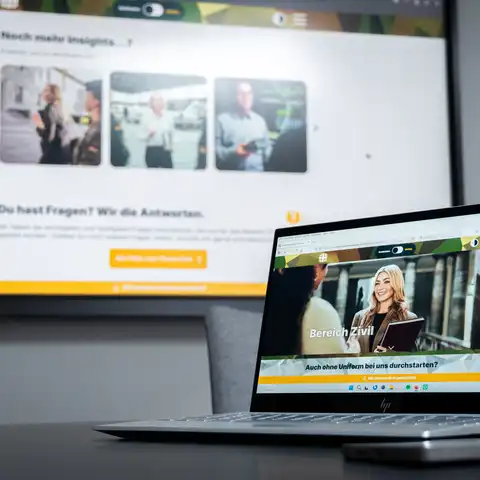 Ein Display an der Wand, auf dem die Karriereseite der Bundeswehr zu sehen ist. Davor ein Laptop, das ebenfalls die Karriereseite zeigt.