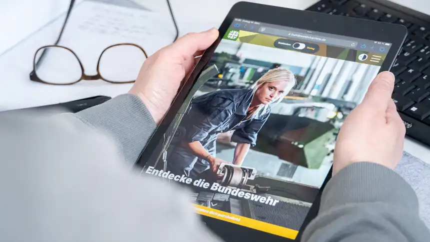 Hände, die ein iPad halten, auf dem die Seite der Bundeswehr aufgerufen ist.