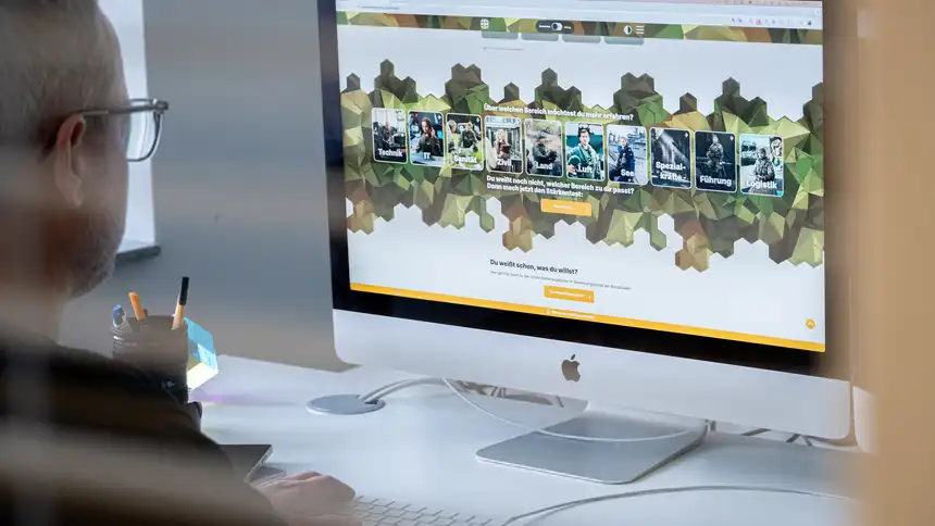 Ein Apple Monitor, der die Karriereseite der Bundeswehr zeigt, davor eine Person, die auf den Bildschirm schaut.