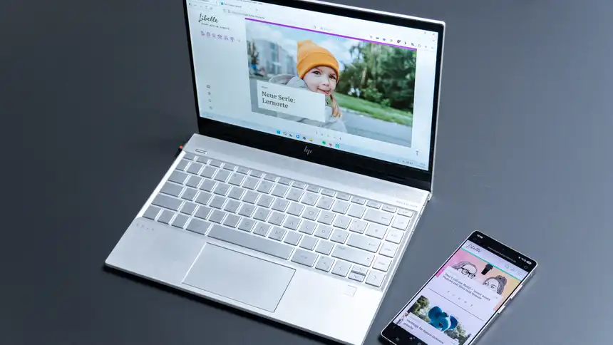 Ein Laptop und ein Smartphone, auf denen die Website des Libelle Magazins angezeigt wird, liegen auf einem Tisch