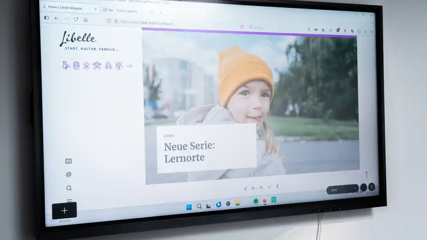 Ein Display an der Wand zeigt die Website des Libelle Magazins.