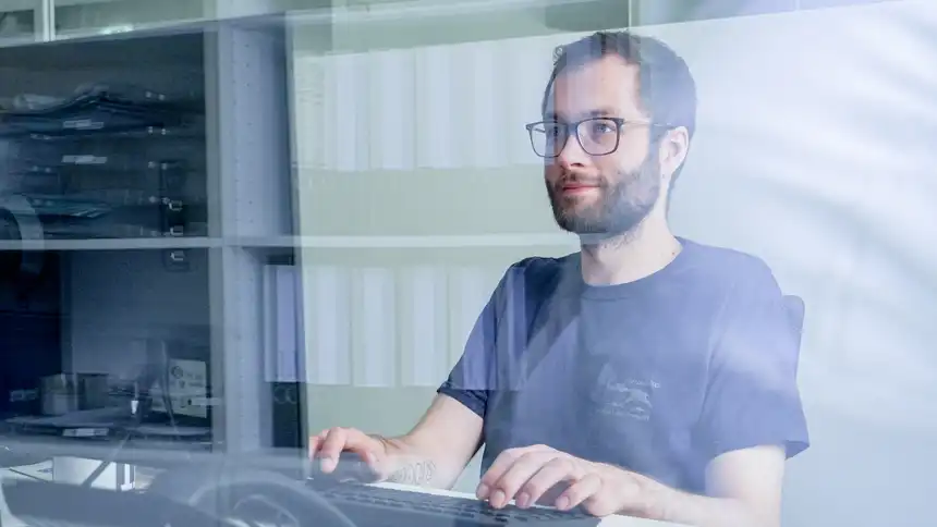 Eine Person sitzt an einem Schreibtisch vor einer Tastatur