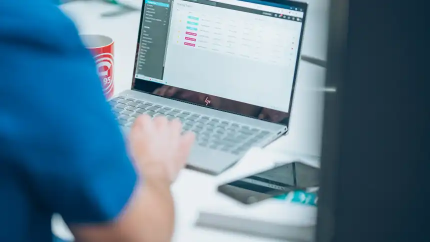 Eine Person sitzt am Schreibtisch vor einem Laptop