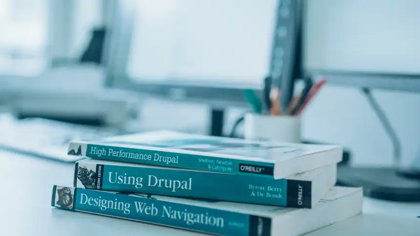 Ein Stapel Fachbücher liegt auf einem Schreibtisch