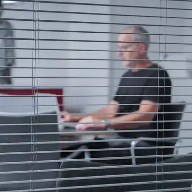 Eine Person sitzt an einem Besprechungstisch und schaut auf ein Laptop