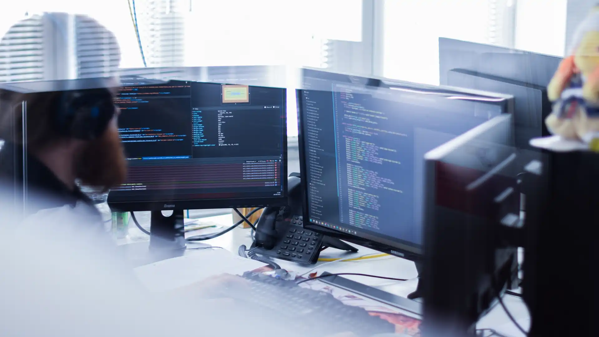 Eine Person mit Kopfhörern sitzt vor einem Monitor